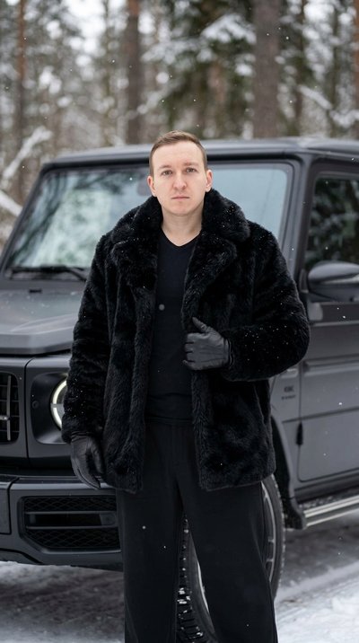 Мужчина в монохроме у Mercedes G-Wagon в снежном лесу